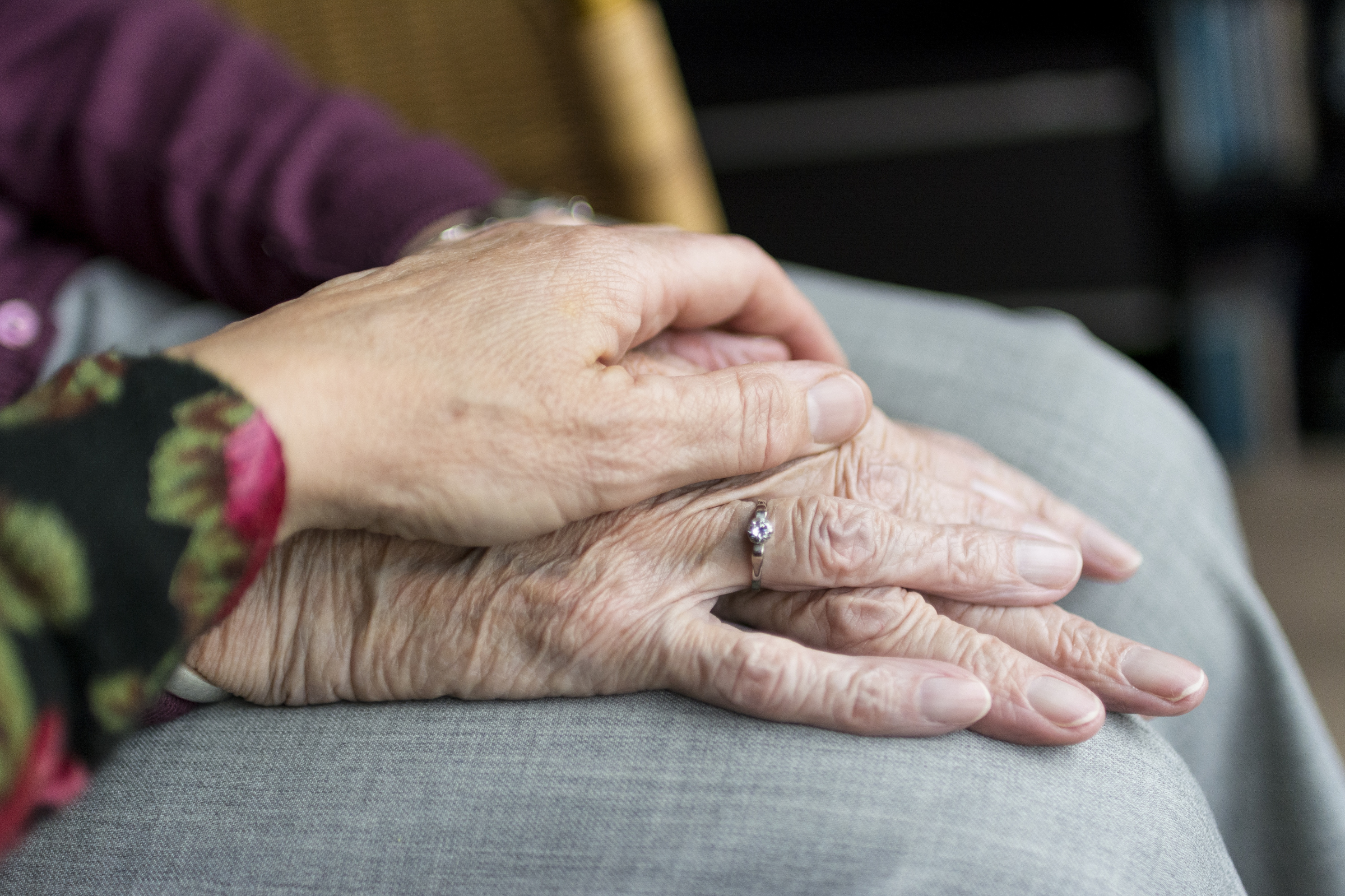 image of senior's hands being comforted by another hand